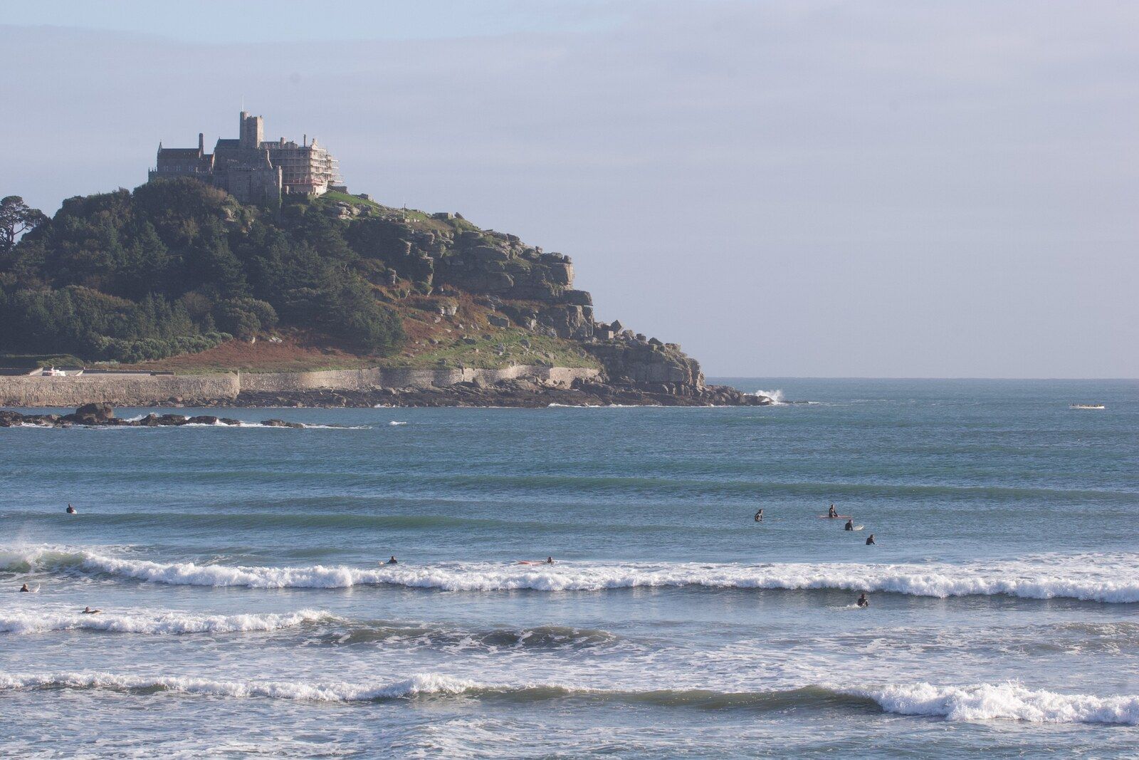 Surfers in small waves at Marazion with St Michael's Mount across the bay